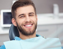 A man smiling in a dental chair after tooth colored fillings