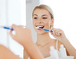 A woman brushing her teeth after tooth colored filling treatment