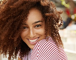 Woman in red and white shirt smiling outside