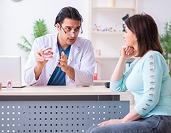 A dentist showing a female patient how the process will work when receiving dental implants in Thorndale