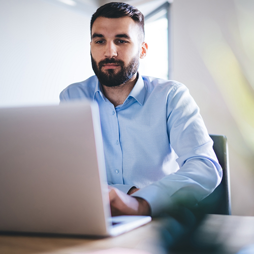 Man in button up shirt typing on laptop