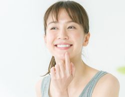 A woman pointing at her mouth and smiling after dental checkup