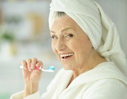 An older woman brushing her teeth