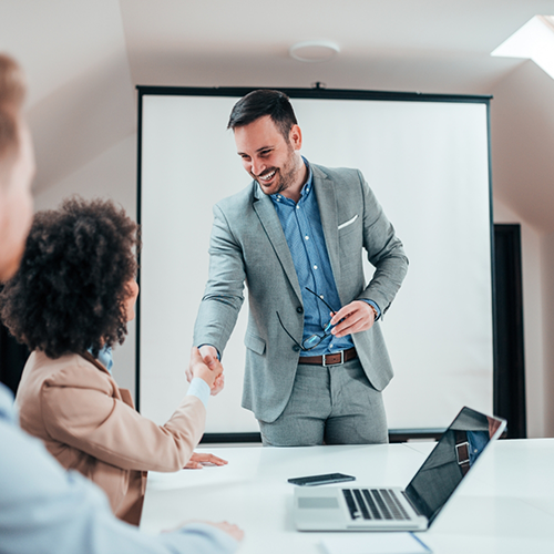 Man in suit shaking woman's hand in meeting