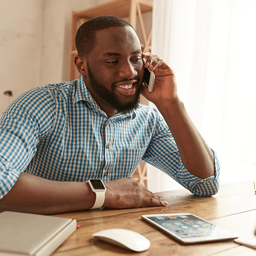 Man sitting at table talking on a cell phone
