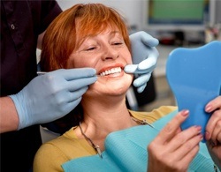An older woman examining her smile after dental crown restoration
