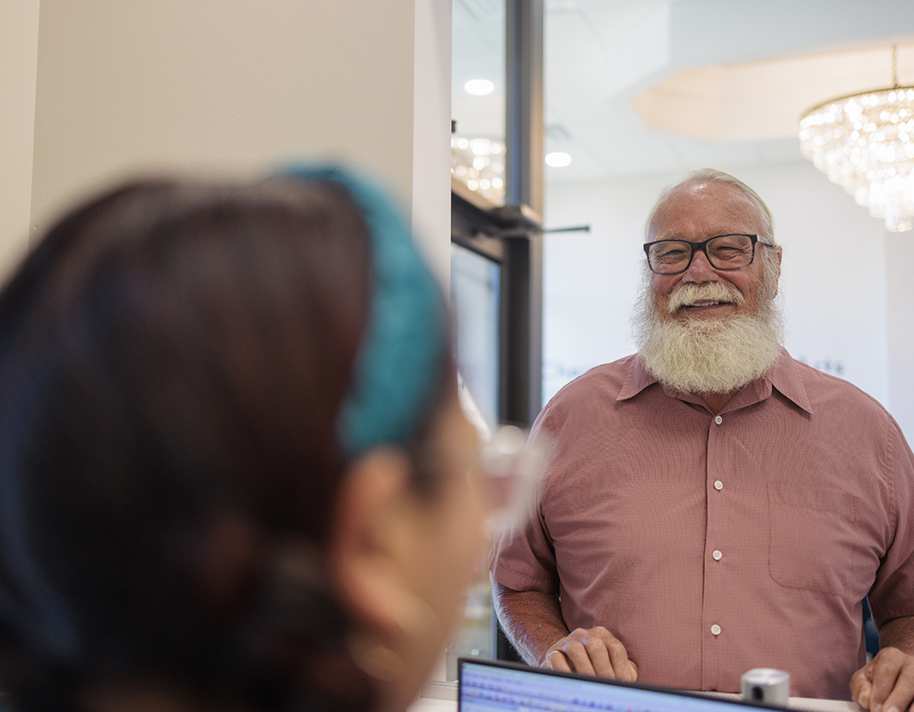 Bearded man with glasses talking to dental team member