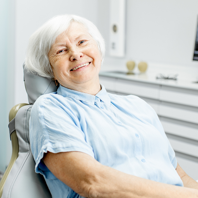 Senior woman sitting in dental chair and smiling
