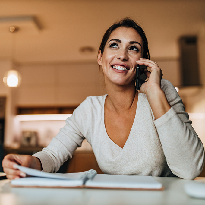 Woman sitting at table and talking on the phone