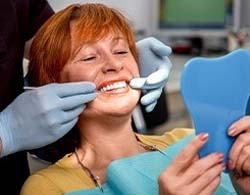 Woman admiring her new implant dentures in Coatesville 