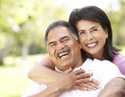 Couple with dental implant retained dentures outside smiling in Thorndale