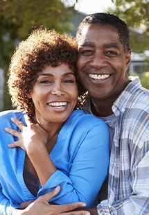 Couple smiling after replacing missing teeth