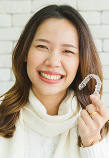 Woman holding up Invisalign tray