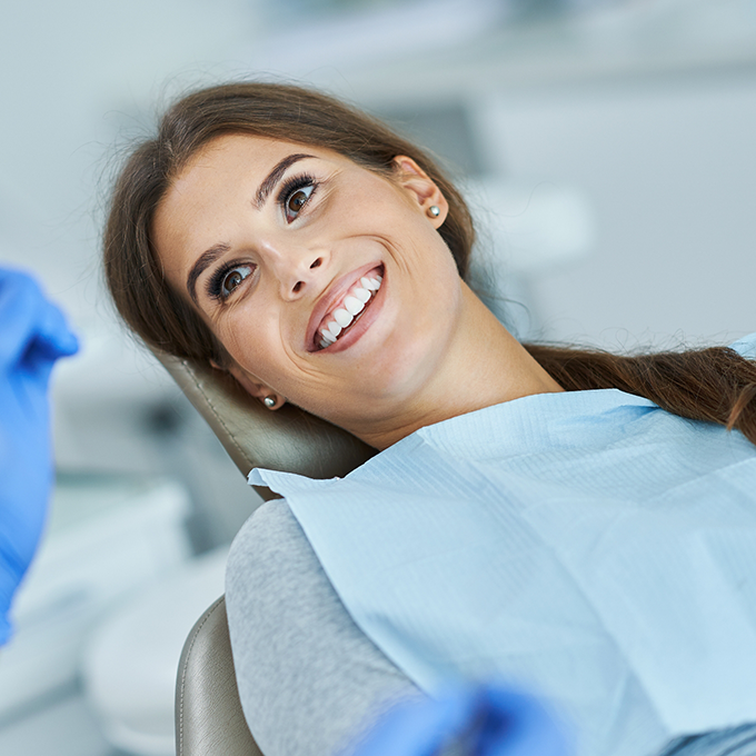 Woman sitting back in dental chair and smiling