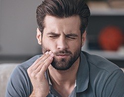 Man in pain holding cheek before root canal therapy
