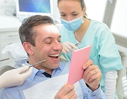 Man looking in mirror after smile makeover