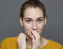 Woman in need of braces covering her smile