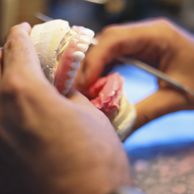 Dental lab technician working with model of teeth