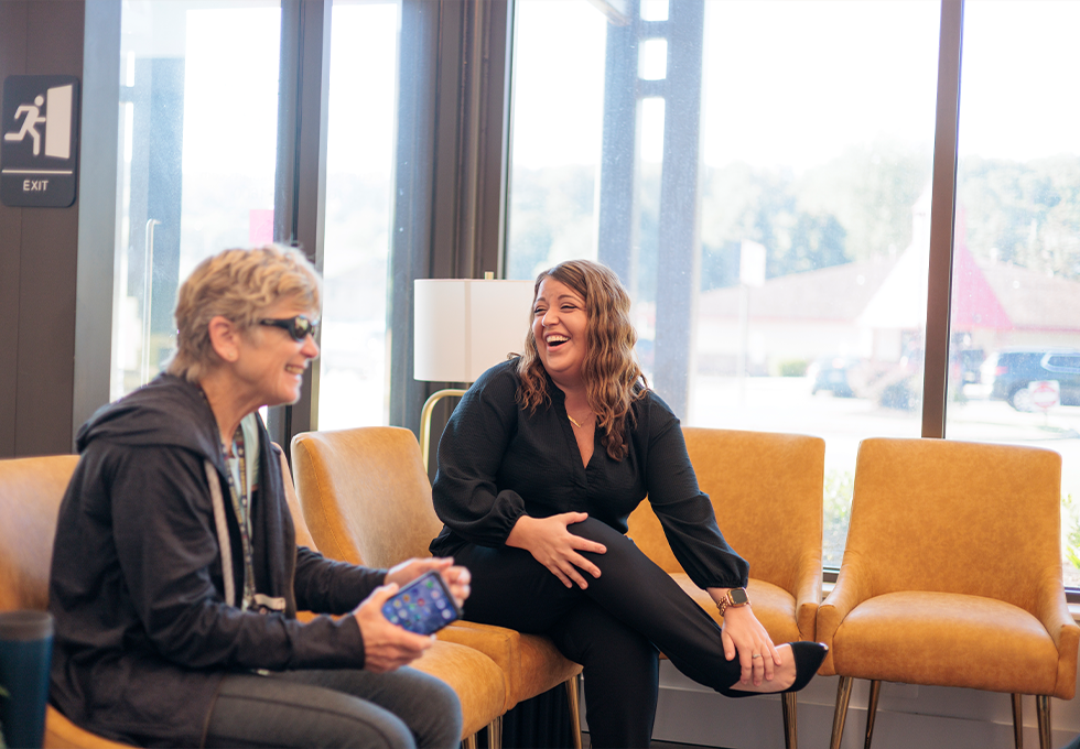 Two women sitting on chairs in reception area