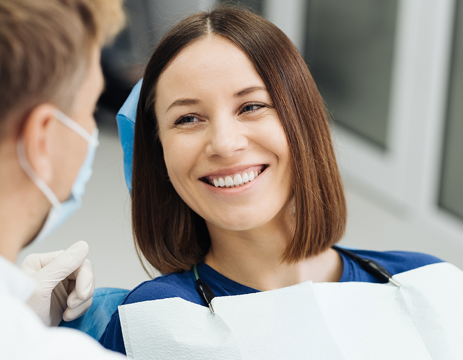 Female patient in dental chair smiling at dentist