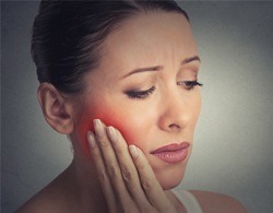 Woman holding the side of her face in pain before root canal therapy