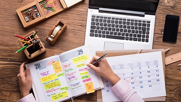 Person writing in a planner book