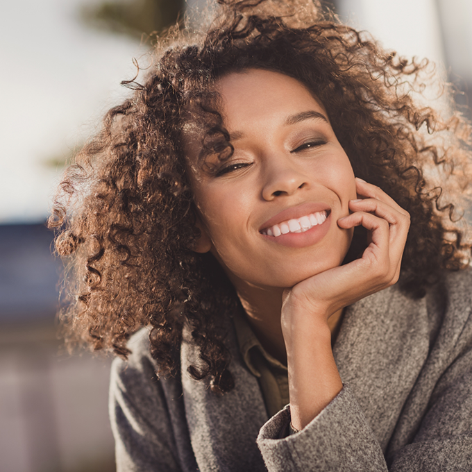 Smiling woman with curly hair and brown jacket