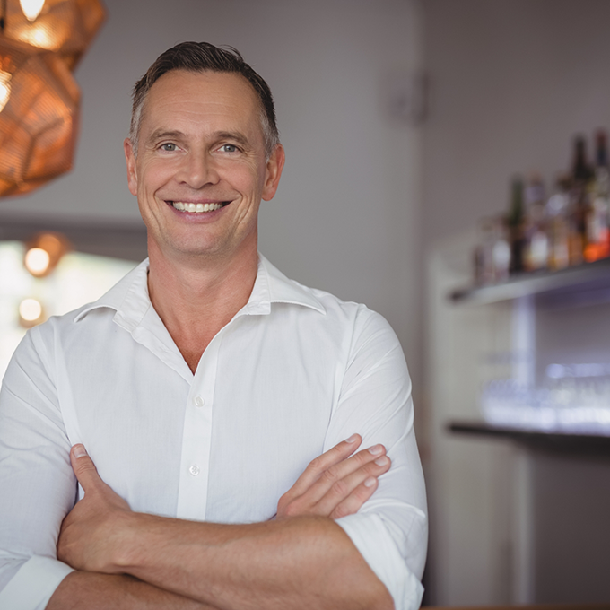 Man in white shirt smiling with arms folded