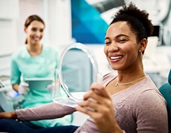 Woman smiling at reflection in small mirror