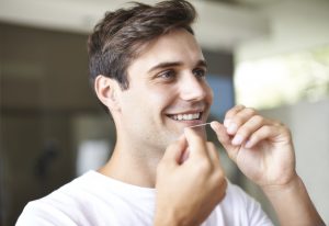 Young man flossing teeth