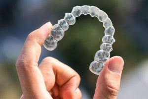 woman holding Invisalign aligner between fingers