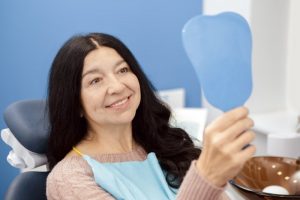 mature woman in dental office admiring her teeth