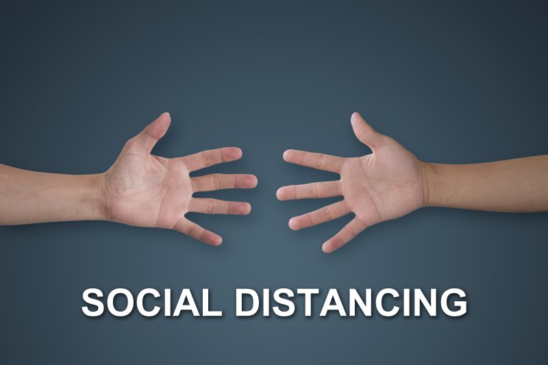 two hands reaching for each other with the words “social distancing” underneath