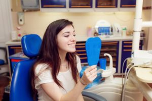 teenage girl looking at her smile in mirror 