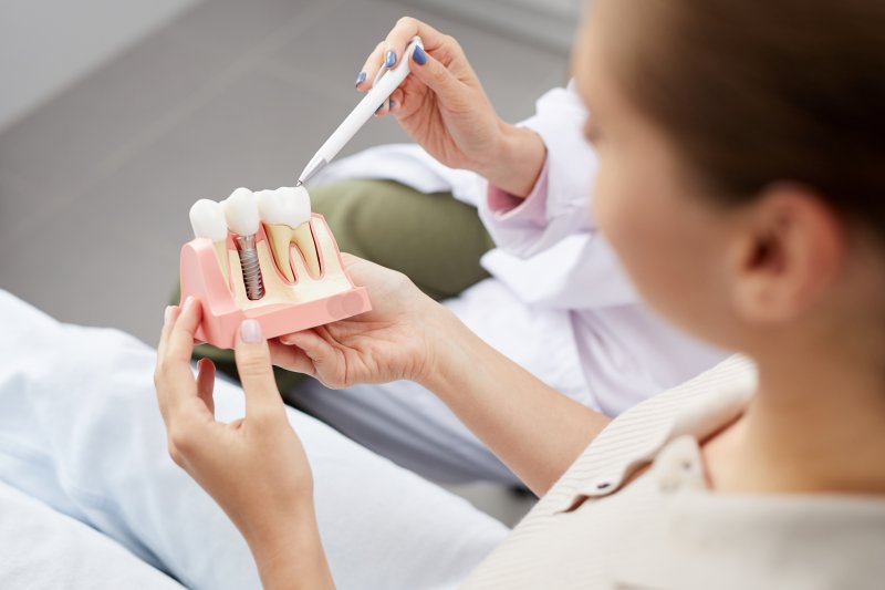 A woman holding an enlarged dental implant model